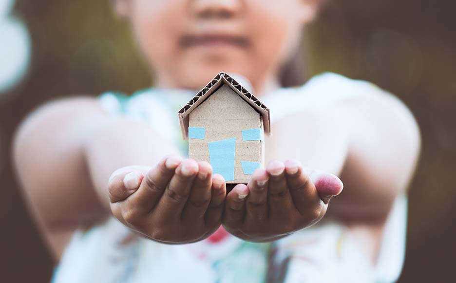 Image representation of affordable housing -- child holding small, paper-made house.