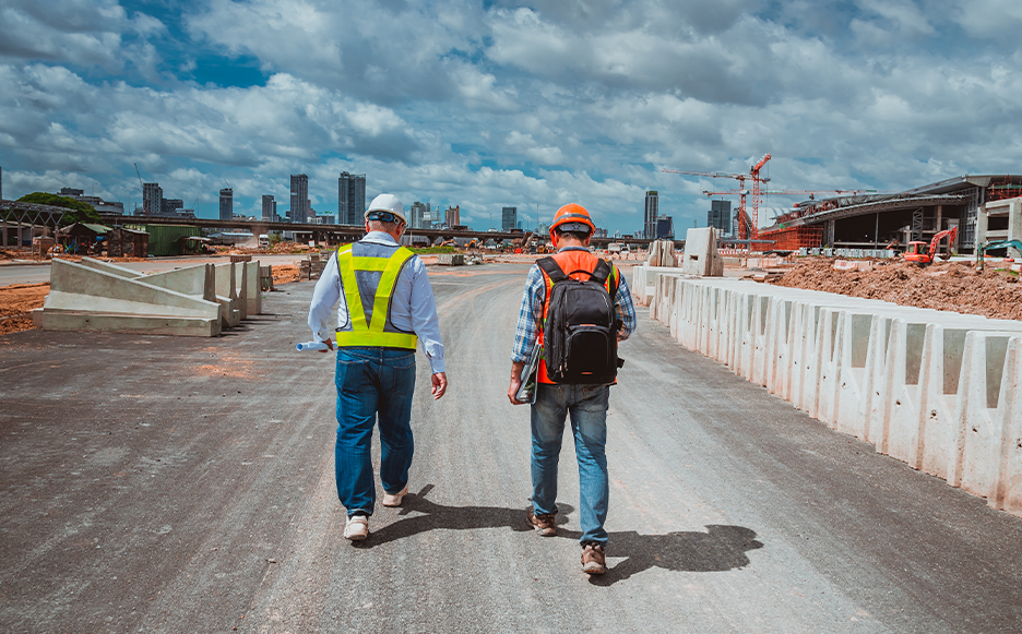 two men in construction outfits walking towards an infrastructure project